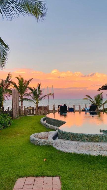 a resort with a pool with the ocean in the background at Pousada San Antonio Praia in Caraíva