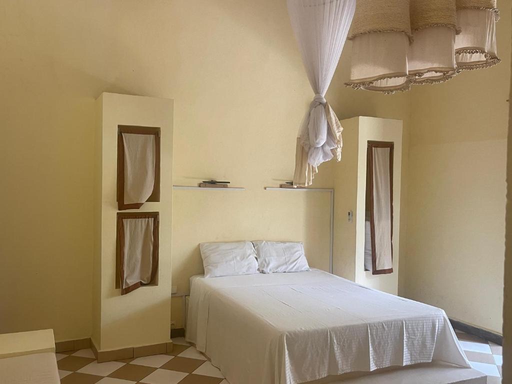 a bedroom with a white bed and a window at Takasira Appart Hôtel Downtown in Fort Dauphin