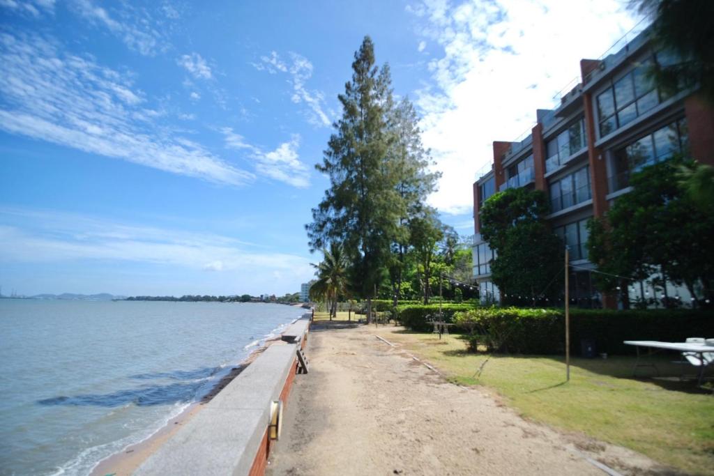 a sidewalk next to the water next to a building at Hommie Home Pattaya in Ban Krathing Lai