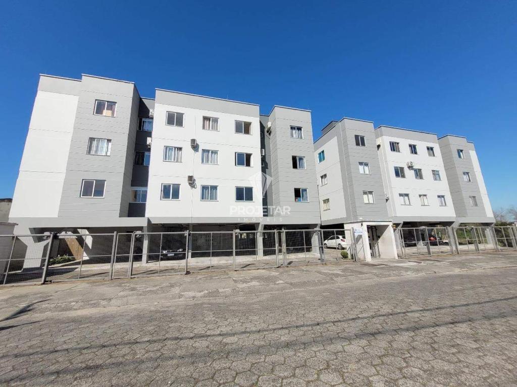a row of tall white buildings on a street at Apartamento 2 quartos Centro de Araranguá in Araranguá