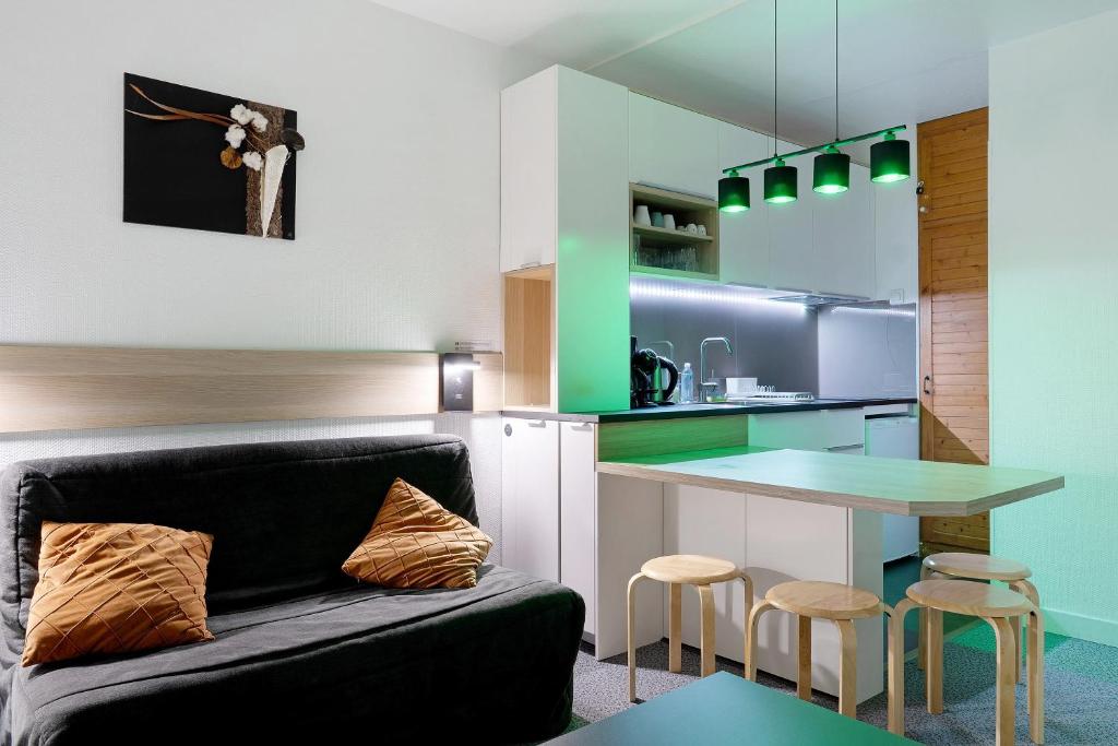 a living room with a couch and a kitchen at Studio Moderne Pied Des Pistes 4 p in La Pierre Saint Martin