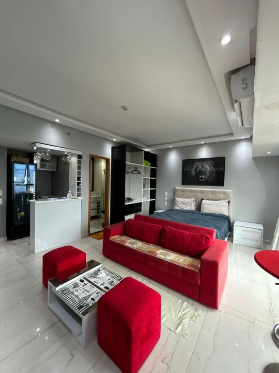 a living room with a red couch and a bed at Tropical Executive Vista Pôr do Sol in Manaus
