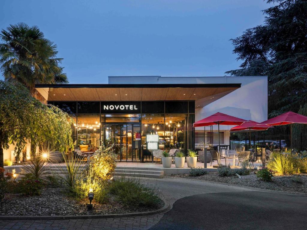 a building with a restaurant with tables and umbrellas at Novotel Rennes Alma in Rennes