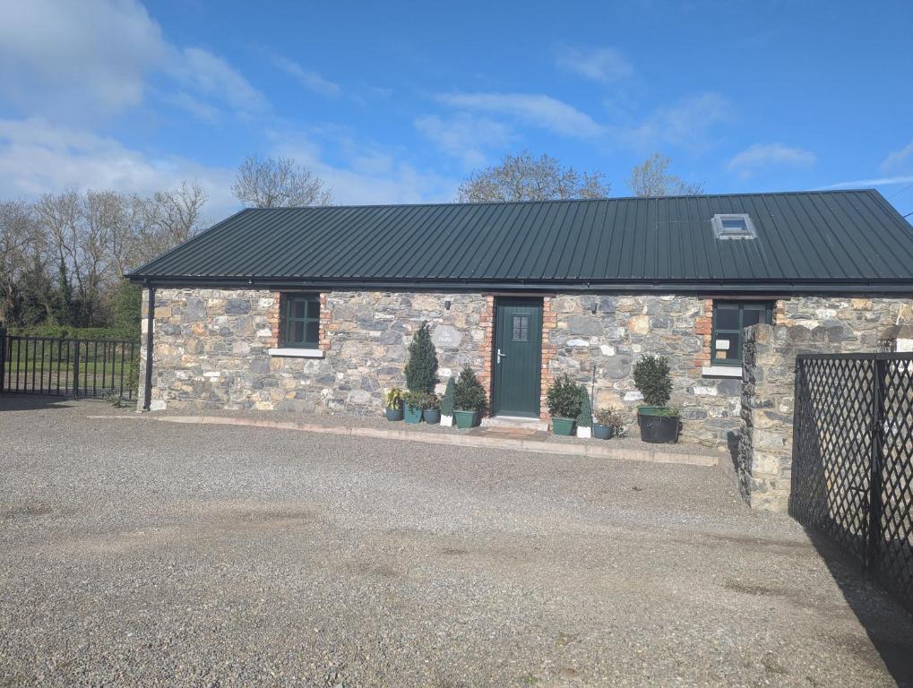 a stone house with a black roof and potted plants at The Stable in Dublin
