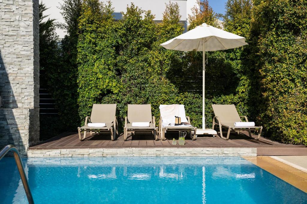 a group of chairs and an umbrella next to a pool at Ixia Pool Villa with sea view roof top in Ixia