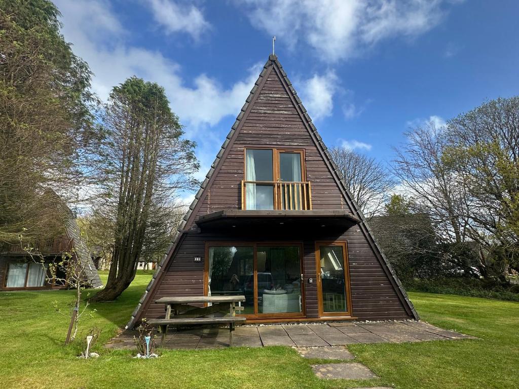 a small house with a triangular roof with a picnic table at Lodge 22, Bodmin Holiday Park, Cornwall in Lanivet