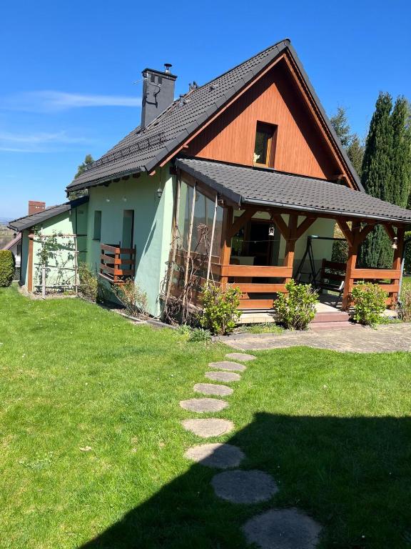 a house with a grass yard in front of it at Domek Leśny Anioł in Jarnołtówek
