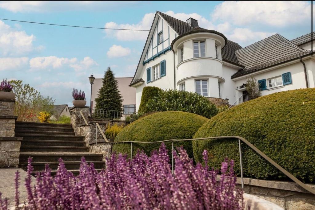 a white house with purple flowers in front of it at Villa Vulkaneifel in Kelberg