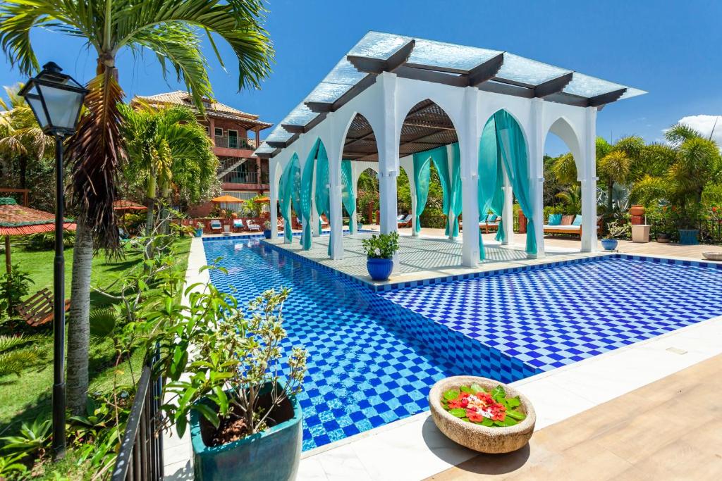 a swimming pool with a gazebo next to a resort at Pedra da Laguna Boutique Hotel SPA in Búzios
