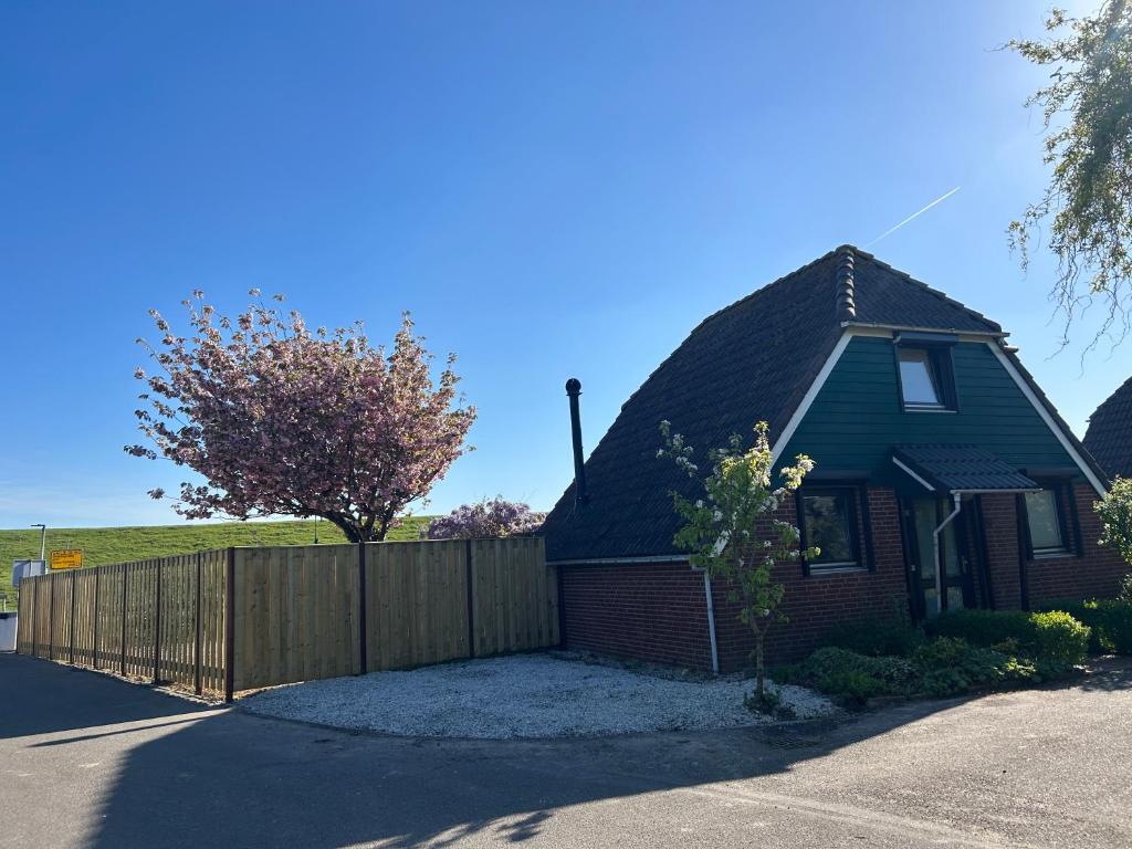 a house with a wooden fence in front of it at Het schapenhuisje in Herkingen