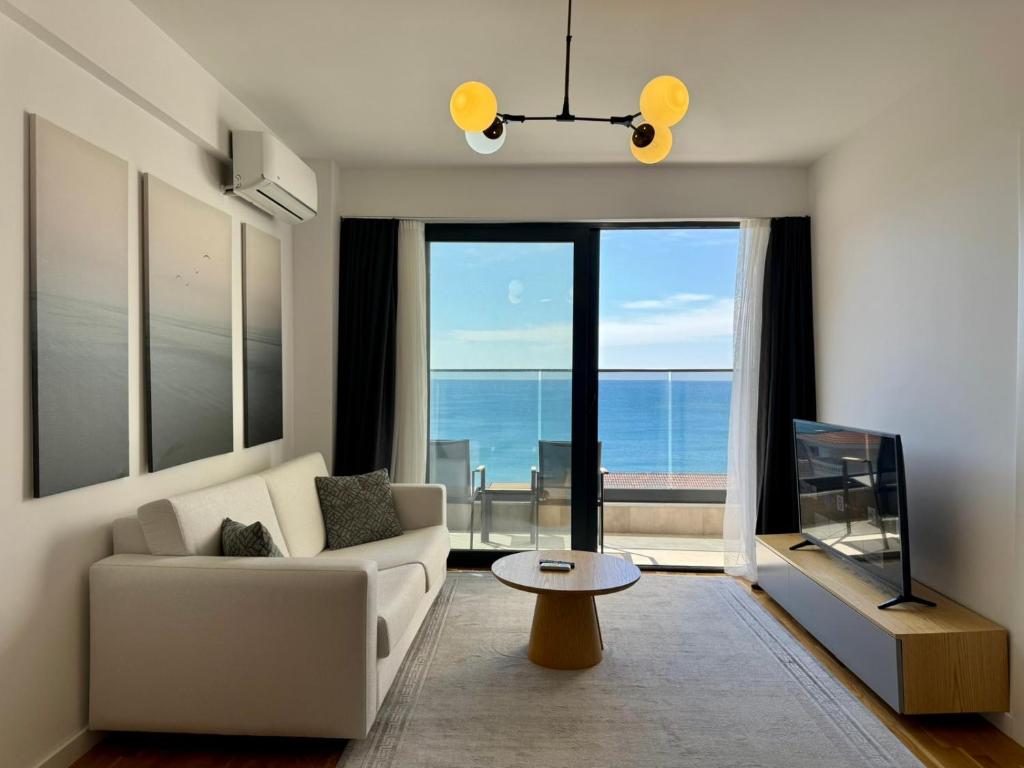 a living room with a white couch and a large window at Beachfront Rafailovici - Budva in Rafailovici