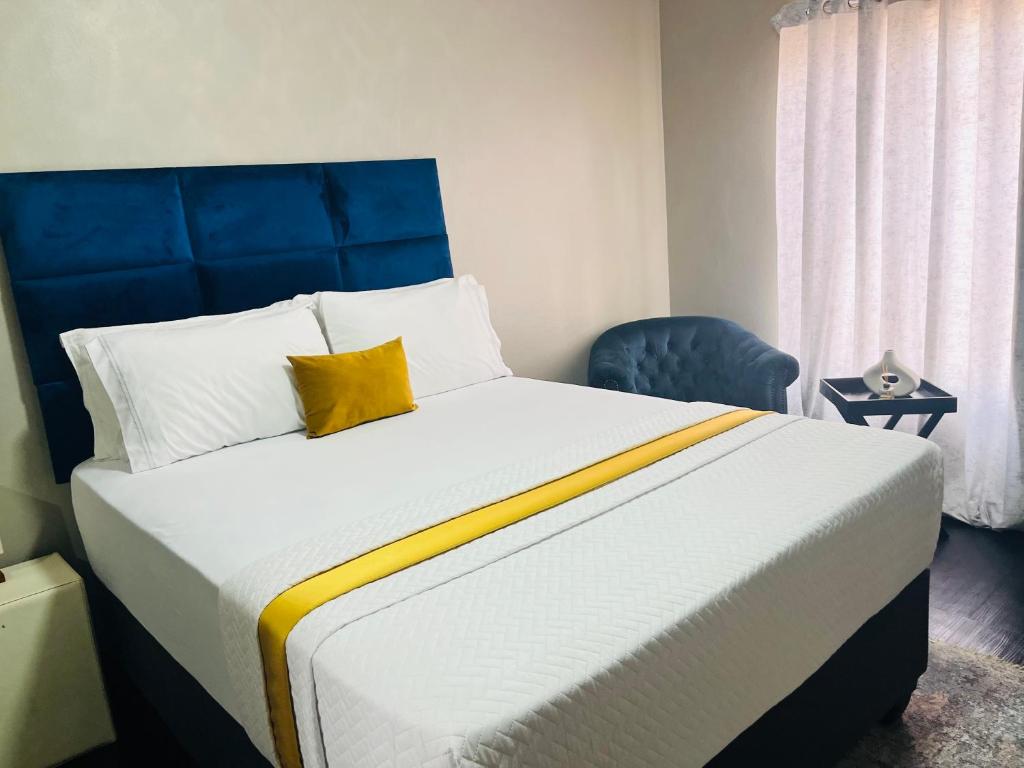 a bedroom with a large bed with a blue headboard at Shiloh Tlokweng in Gaborone