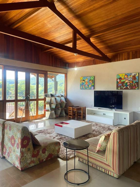 a living room with a couch and a tv at Refúgio Alto do Pinhal in Santo Antônio do Pinhal