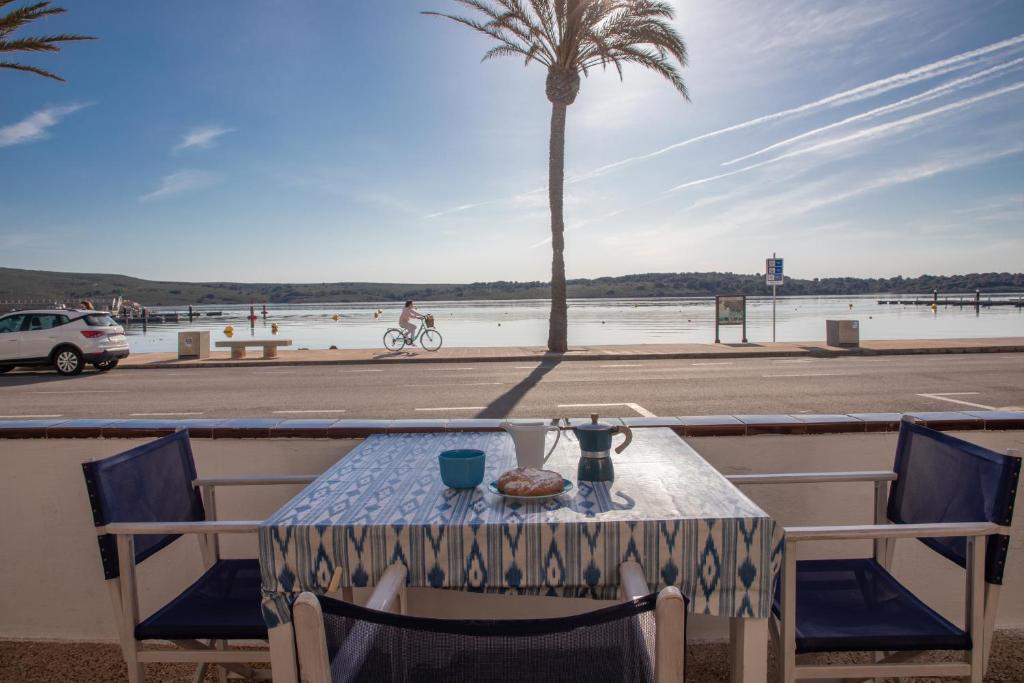 a table on a balcony with a palm tree at SOL NAIXENT in Fornells