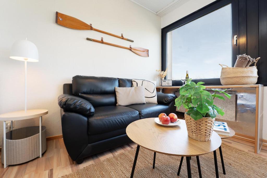 a living room with a black leather couch and a table at Strandhaferweg 7 Beach Apartment Fehmarn in Burgtiefe auf Fehmarn 