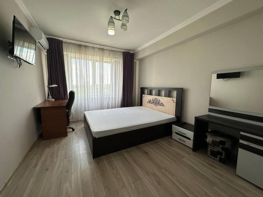 a bedroom with a bed and a desk and a television at DOR ApartHotel in Chişinău