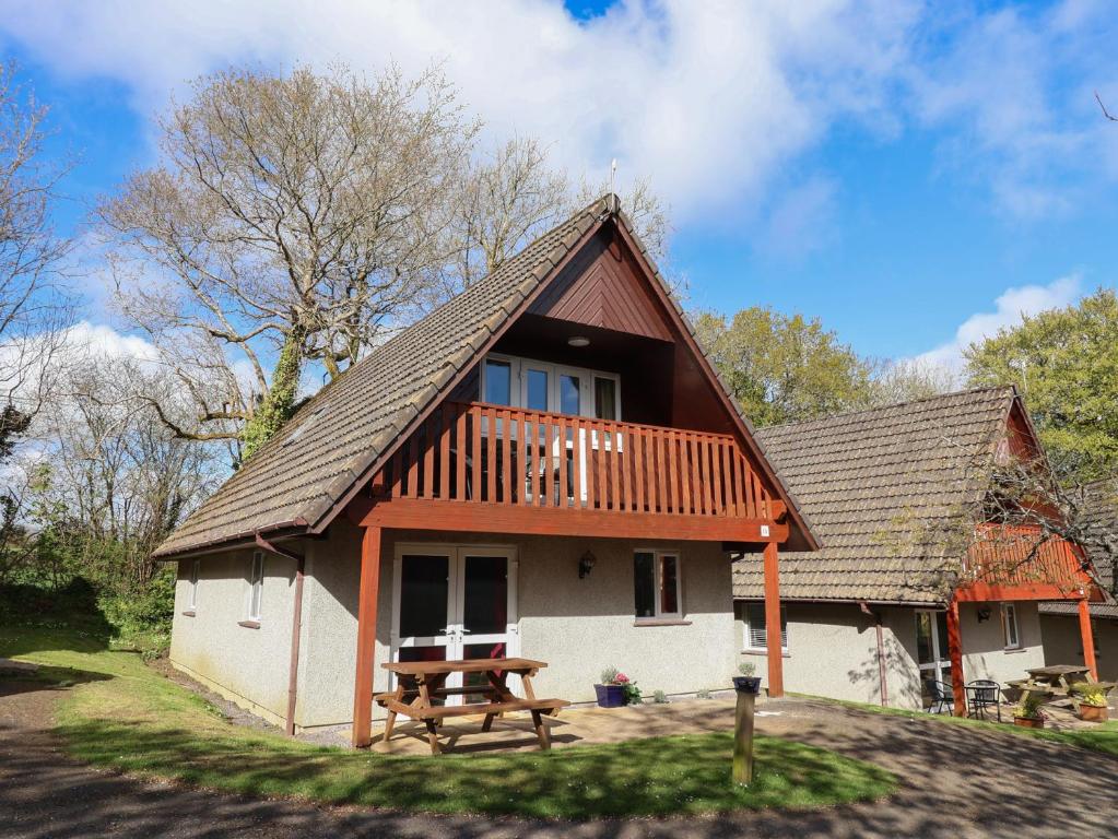 a house with a wooden roof and a picnic table at Mayfly Lodge in Bodmin