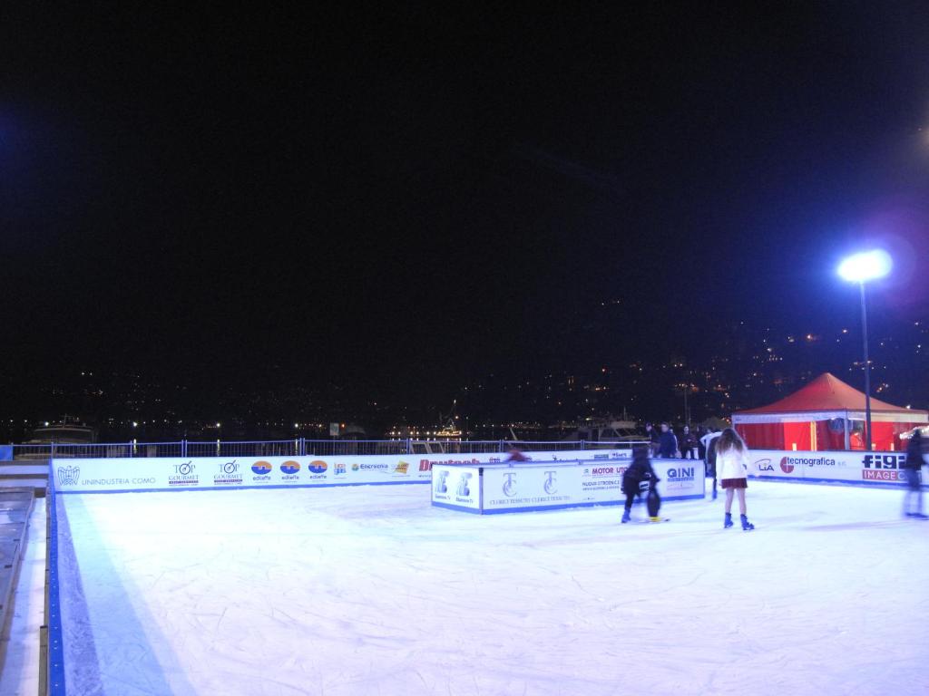 a group of people skating on an ice rink at night at Como Luxury Rooms in Como