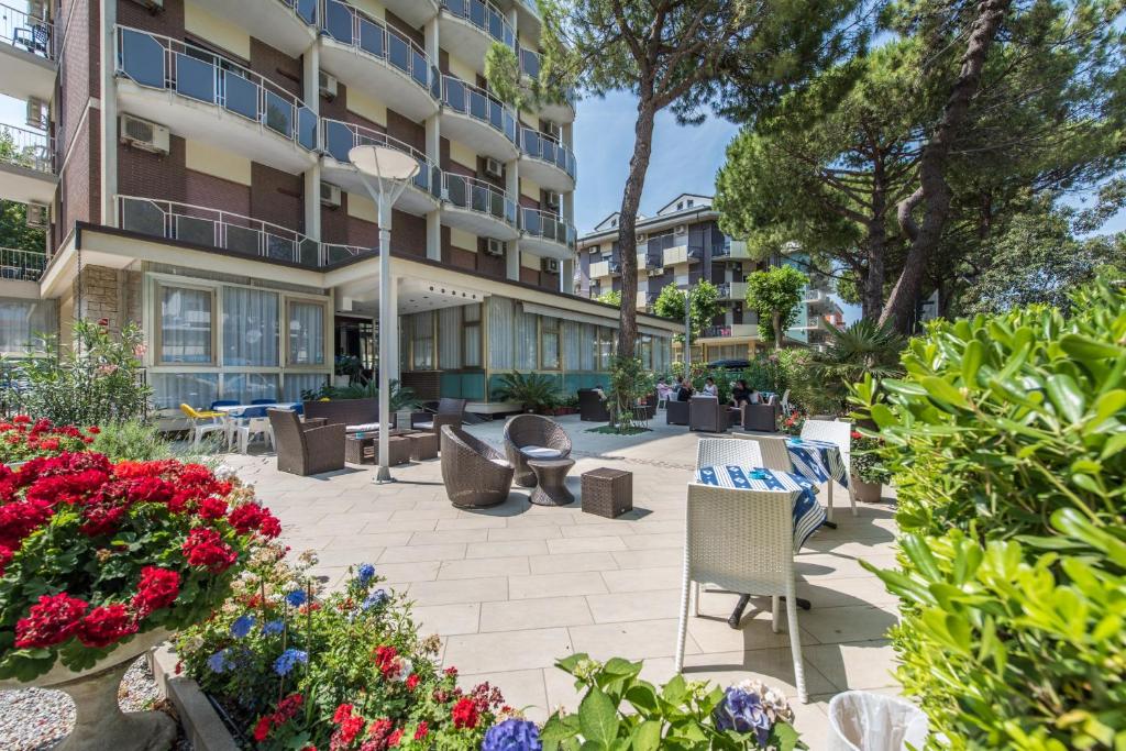 une terrasse avec des chaises et des fleurs devant un bâtiment dans l'établissement Hotel Palladio B&B, à Cervia