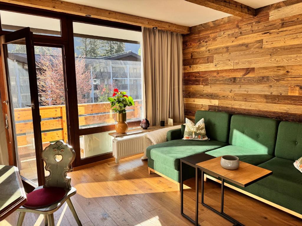 a living room with a green couch and a window at Grubhof Schlosspark, Chalet-Stil mit Pool und Bergblick - Air Conditioner in Sankt Martin bei Lofer