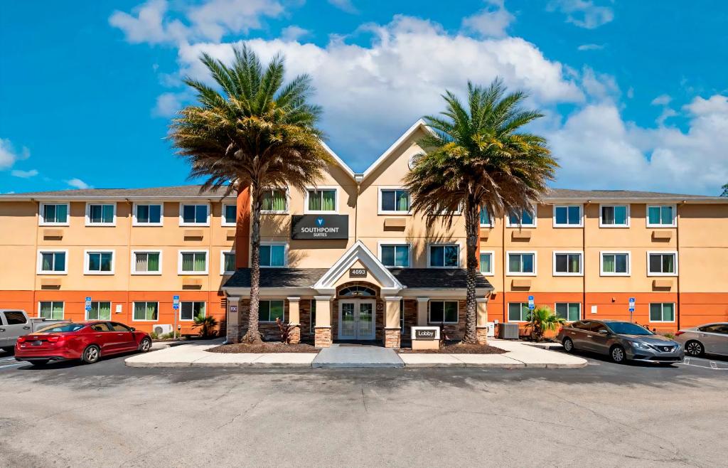 an apartment building with palm trees in front of it at Southpoint Suites Jacksonville in Jacksonville