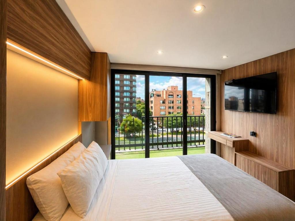a bedroom with a large bed and a large window at ApartaSuite City Bog Usaquén in Bogotá