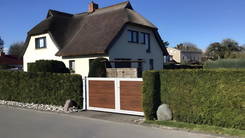 a white house with a wooden gate in front at Ferienwohnung Brunk in Altefähr
