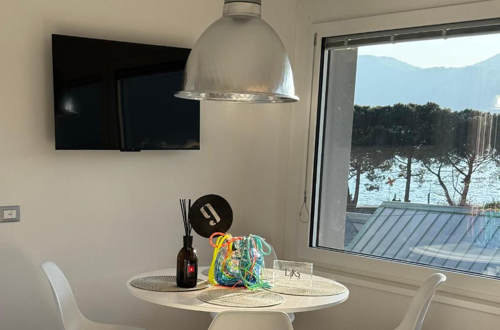 a table and chairs in a room with a window at L4K3 Luxury Apartment - Lake View, Free Pool, Balcony, 50 m to Lake & Historic Center, 90 m2 in Pisogne