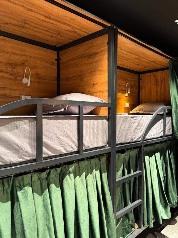two bunk beds in a room with green curtains at The Loft Hostel in Tashkent