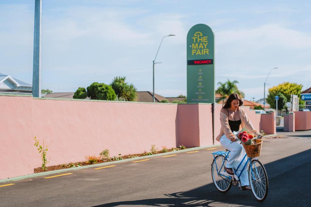 a woman riding a bike with a basket of flowers at The Mayfair in Hastings