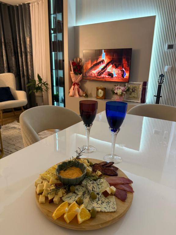 a plate of food and two wine glasses on a table at Apartman Centar in Teslić