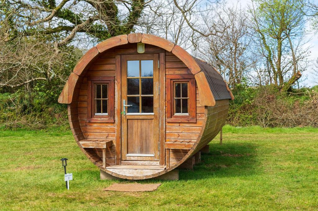 Barrel Cabin 1 في سانت أوستيل: كوخ خشبي صغير بباب في العشب