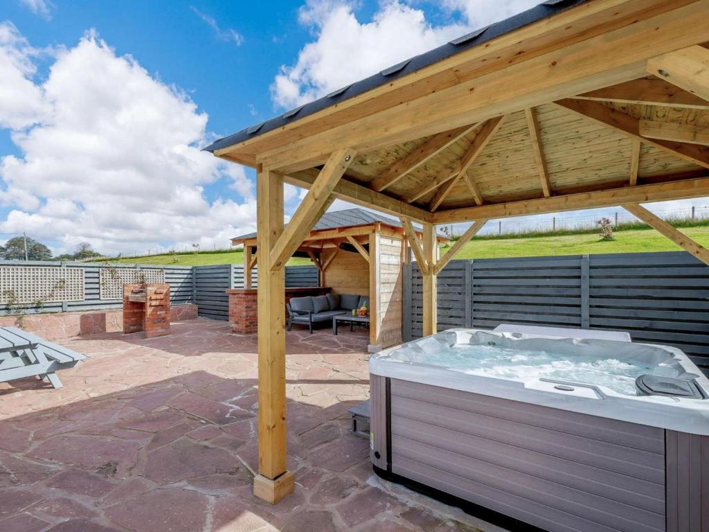a hot tub under a wooden roof on a patio at 3 Bed in Alexandria oc-88758 in Balloch