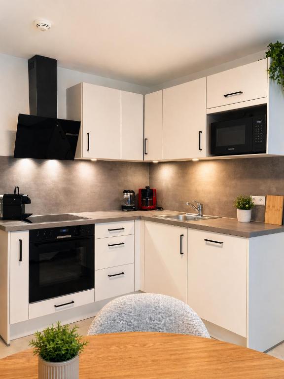 a kitchen with white cabinets and a wooden table at Sindelfingen Apartments in Sindelfingen