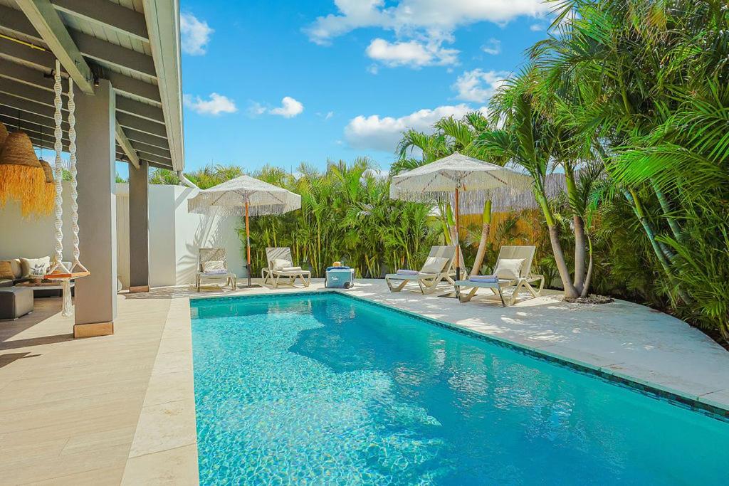 a swimming pool with two chairs and umbrellas at Walk to Beach - Private Pool Villa in Palm-Eagle Beach