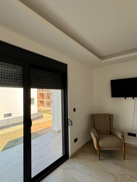 a living room with a chair and a sliding glass door at Apartmani Edi Ulcinj in Ulcinj