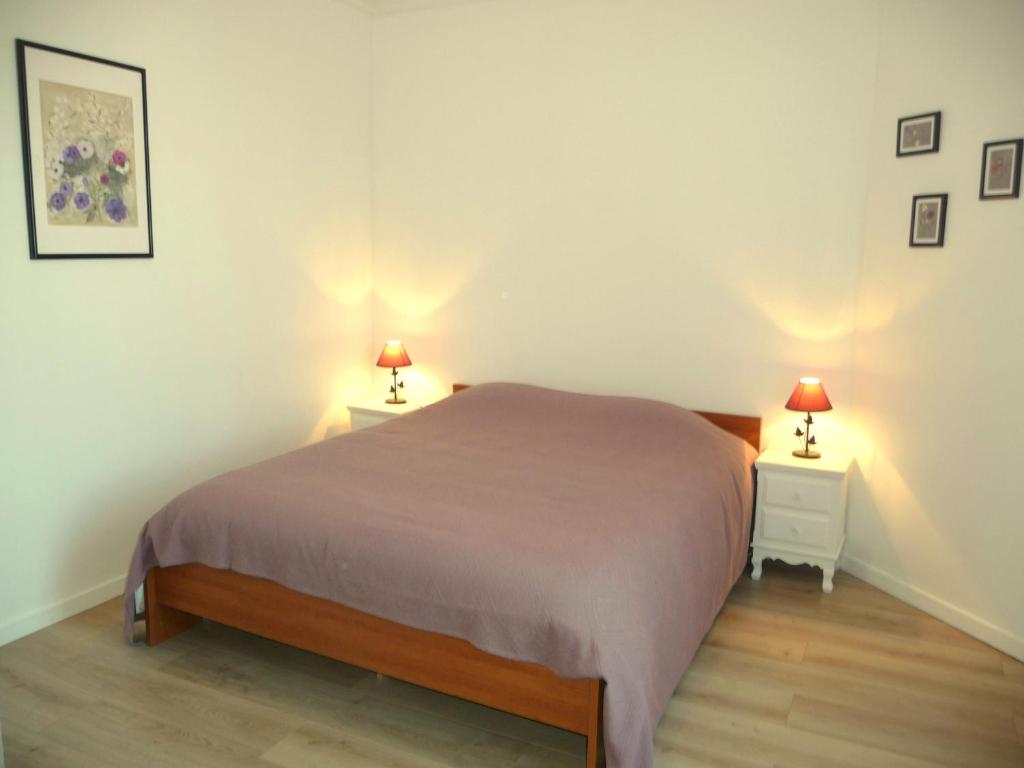 a bedroom with a bed and two night stands with lamps at Tourelle in Gagny
