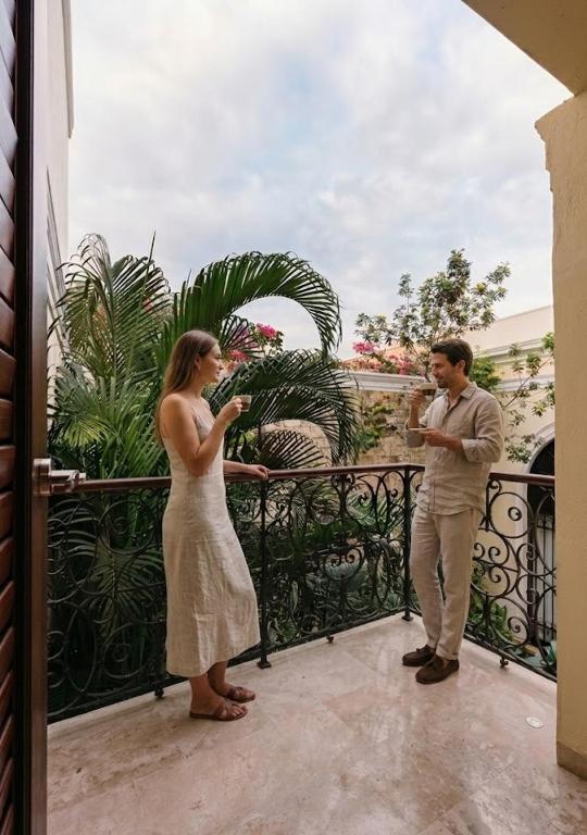 a man and a woman standing on a balcony at La Casa del Centro, Mérida by Cercana in Mérida