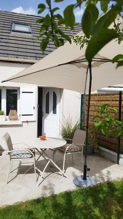 a table and chairs under a white umbrella at Maison Auguste - cosy - terrasse in Verberie