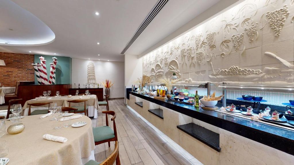 Fine dining restaurant with buffet counter, round tables, and decorative wall relief.