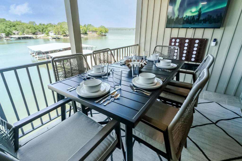 a table on a balcony with a view of the water at Sunset Lakefront Retreat with Luxe Upgrades in Osage Beach