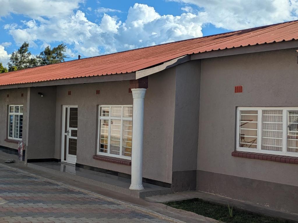 a building with white windows and a red roof at Maneya Apartments in Kabwe