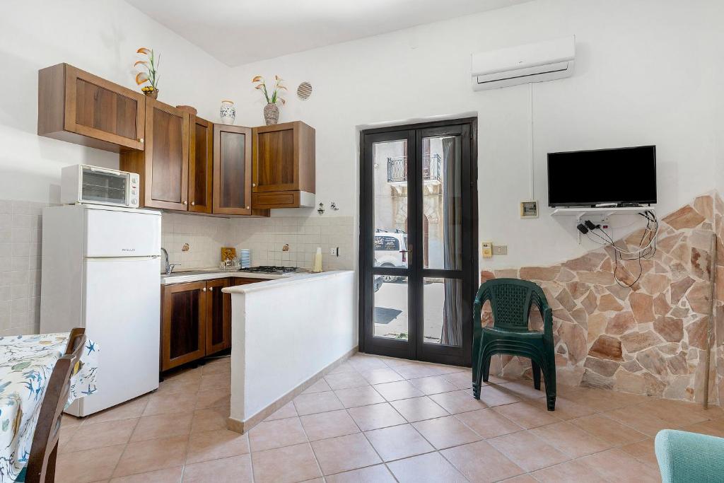 a kitchen with a refrigerator and a table with a chair at Casa Sciura in San Vito lo Capo