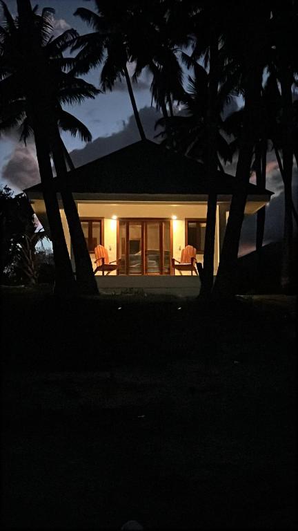 a house with two chairs and palm trees at night at Rancho Primavera in Cuatro Esquinas