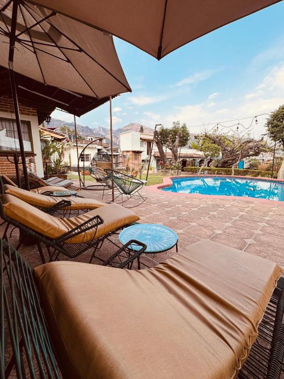 a group of chairs and umbrellas next to a pool at Hotel posada el paraíso in Tepoztlán