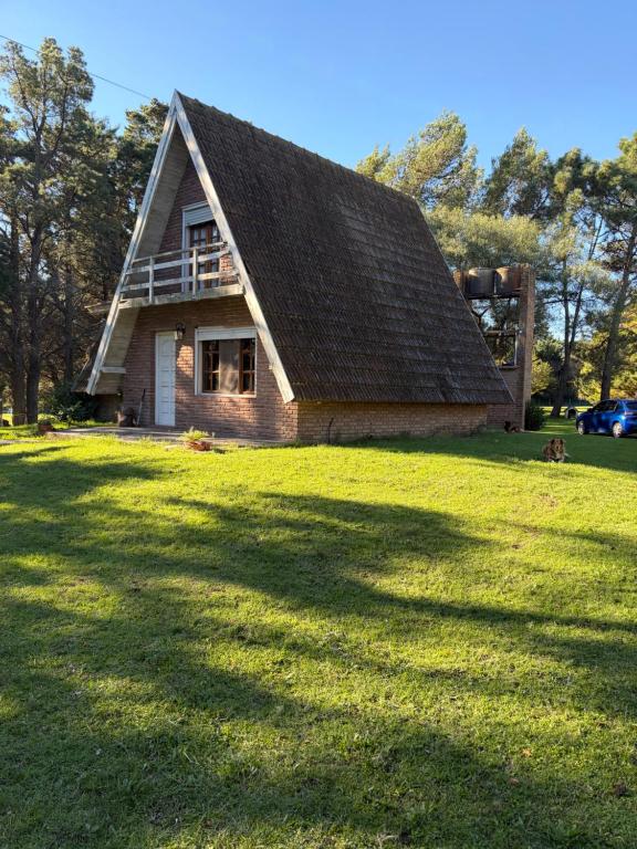 a house with a gambrel roof on a grass field at cabañas los juanes in Tres Arroyos