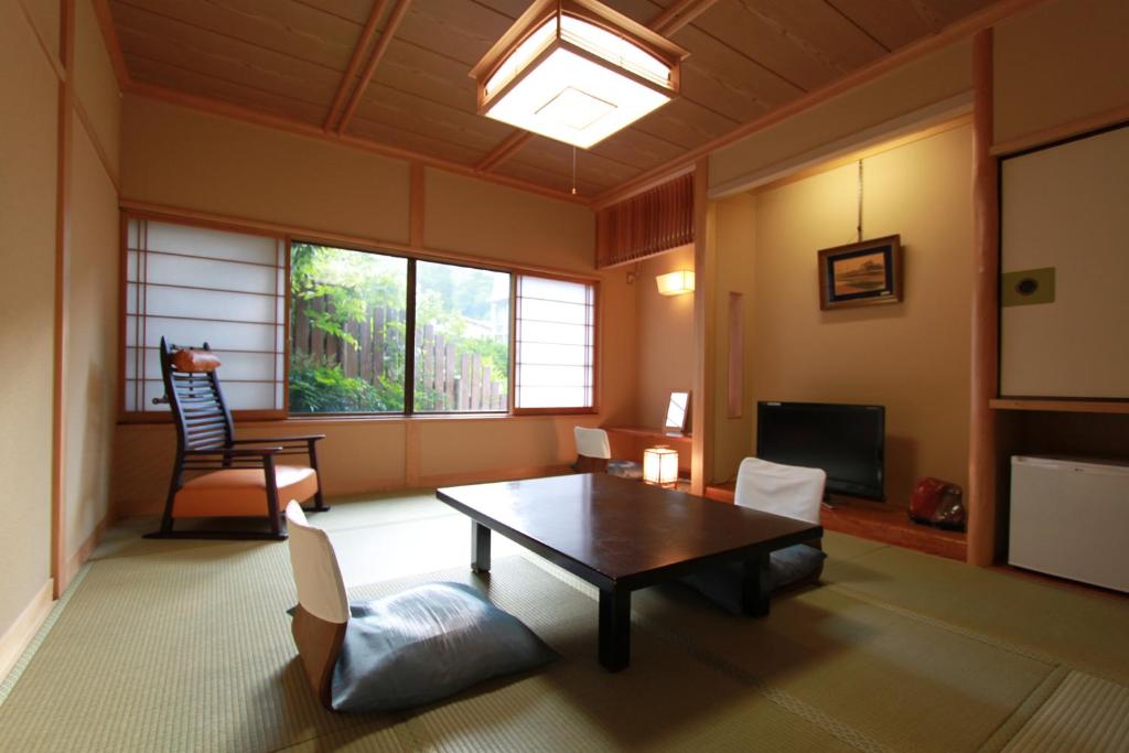 a living room with a table and chairs and a television at 温泉旅館 湯さか荘 in Hakone