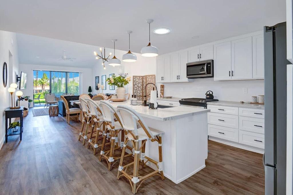 a kitchen with white cabinets and a kitchen island with chairs at Courtyard-Patio-Moutain and V3872-Holly House in Palm Desert