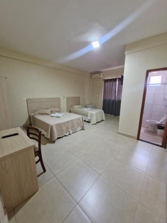 a large room with two beds and a bathroom at Hotel Dom Mineiro in Curvelo