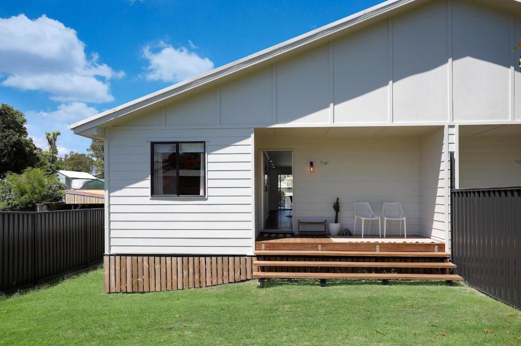 a white house with two chairs on a deck at Amity Duo - Roys in Amity Point